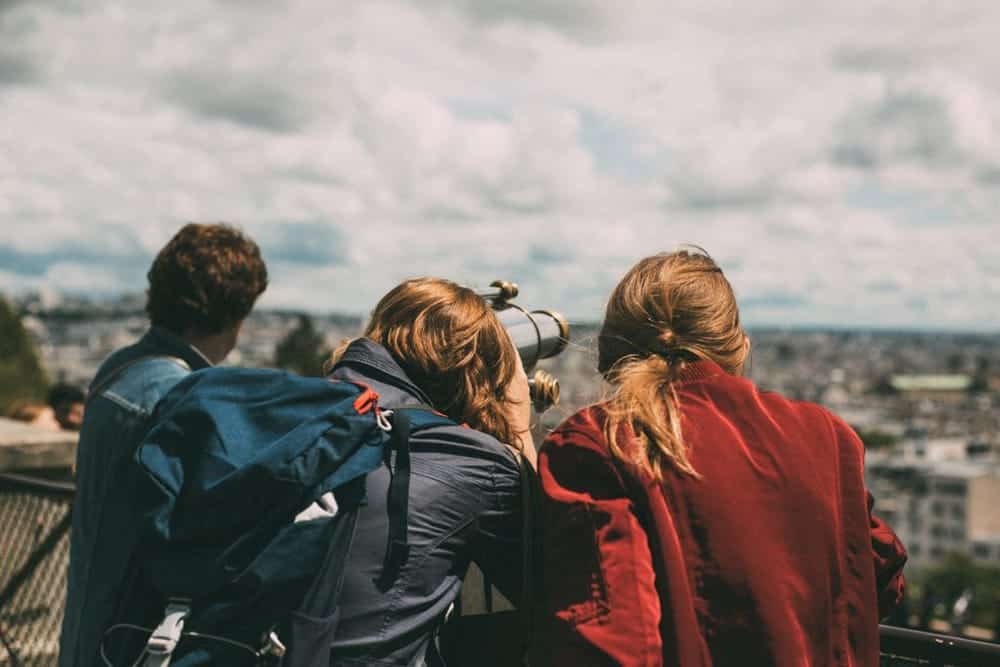 Three young people observing the views from the top of a hill